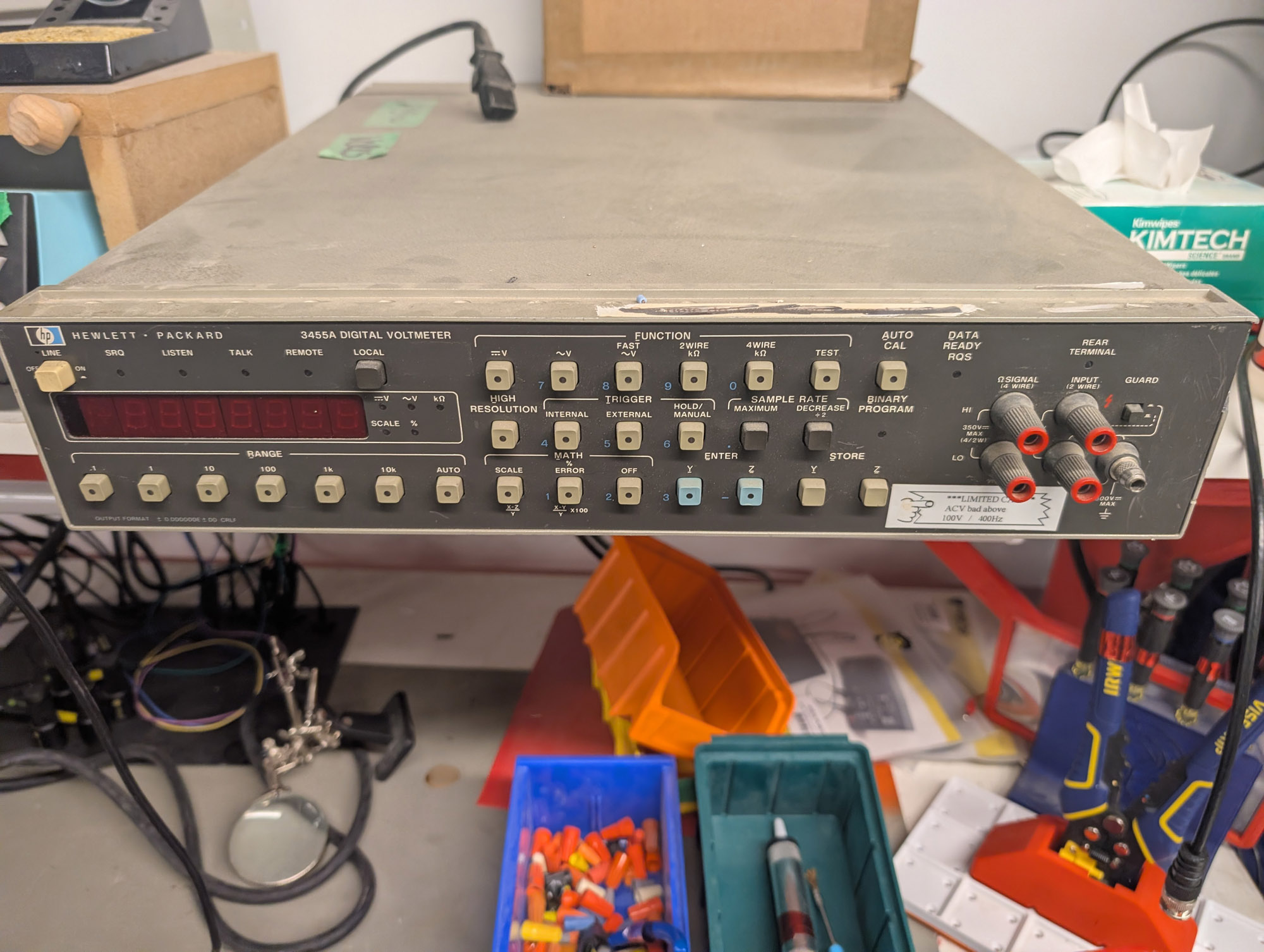 A benchtop digital multimeter with the old Hewlett-Packard logo and "HEWLETT-PACKARD 3455A DIGITAL VOLTMETER" above a 7-digit red LED display. A large number of buttons are below and to the right of the screen, and 4 input terminals are to the far right.